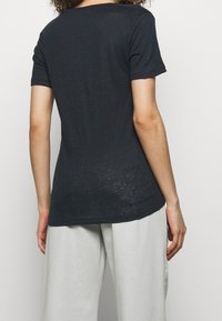 Black, short-sleeve T-shirt made of a soft, lightweight fabric. Features a rounded neckline and a slightly longer back hem.