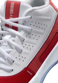 Witte en rode sneaker met een glad leren bovenwerk met perforaties, rode accenten en witte veters. Geweven details op het zijpaneel.