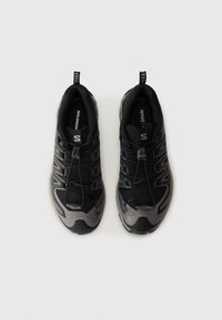 Zwarte sportieve schoenen met een bovenwerk van mesh, versterkte neuscap, elastische veters en een gestructureerde zool met contrasterende grijze accenten.
