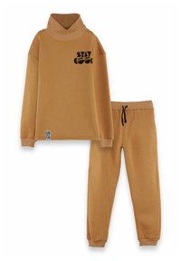 Beige sweatshirt med hög krage och svart text "STAY COOL"; matchande sweatpants med elastisk midja och svart dragsko. Mjuk tyg.