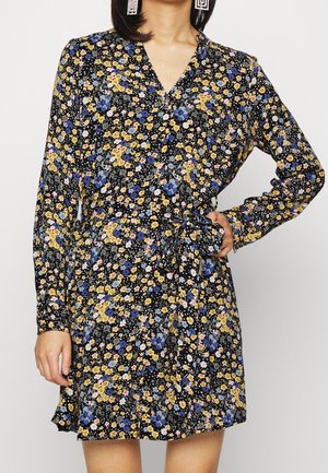 Kwiatowa sukienka z długimi rękawami, czarne tło i wielokolorowe kwiaty. Dekolt w serek, taliowanie z detalem wiązania, lekka tkanina.