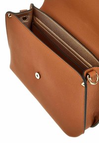 Sac en cuir marron à finition texturée, avec un fermoir à pression doré, des poches intérieures et des bords en noir.