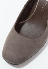 Escarpin pour femme en daim marron avec un bout arrondi, une texture lisse et un talon bas et solide. L'intérieur présente un design simple et incurvé.