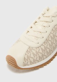 Beige sneakers med struktureret stof med MK-mønster, glatte læderdetaljer og en gummisål med zigzag mønster.