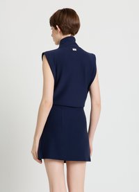 Marineblaues ärmelloses Kleid mit hohem Kragen und tailliertem Schnitt. Glatter Stoff, minimale Verzierungen und ein Schnitt, der oberhalb der Mitte des Oberschenkels endet.