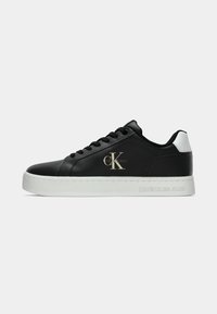 Sneaker nera a basso profilo con suola e accentuazione del tallone bianchi, che presenta il logo Calvin Klein Jeans di lato e il marchio impresso sulla suola.