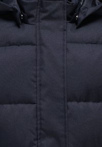 Temno modra navtična puhovka z vzorcem kviltanja, ki ima visok ovratnik in zadrgo. Material je videti gladek s lahko teksturo.