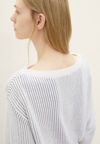 Weiß gestreifter Strickpullover mit weitem Ausschnitt und gerippter Struktur. Das Design zeichnet sich durch einen lockeren Schnitt und einen weichen Abschluss aus.