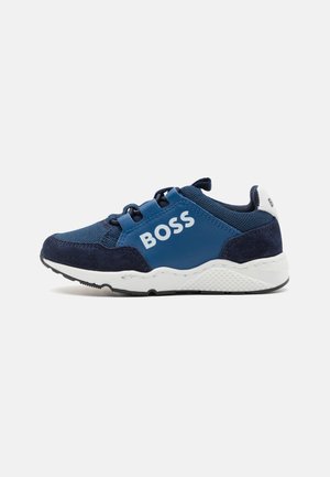 Marineblå sneakers med net og ruskindmateriale, med et hvidt logo, elastiske snørebånd og en struktureret hvid sål.