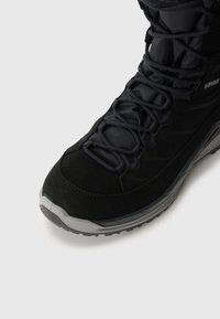 Stivaletto alla caviglia in suede nero e sintetico con design testurizzato, lacci eleganti e suola in gomma grigia, dotato di punta rinforzata e imbottitura.