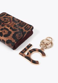 Portafoglio con stampa leopardata e interno bordeaux, dotato di hardware dorato e un portachiavi abbinato con accenti dorati a forma di "C."