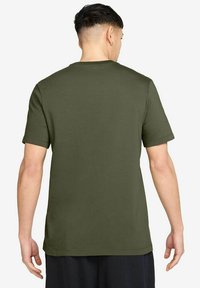 Olijfgroen T-shirt met korte mouwen, gemaakt van zachte katoen. Kenmerkt zich door een ronde halslijn en een rechte snit, zonder zichtbare logo's of patronen.