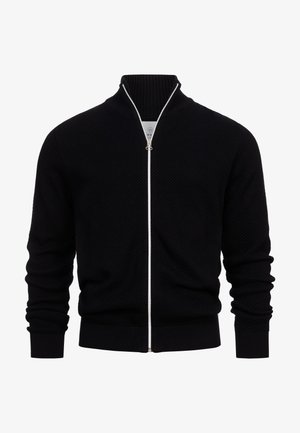 Fekete cipzáras pulóver texturált kötött mintával, bordázott gallérral és mandzsettával, valamint kontrasztos fehér cipzárral. Mintázat vagy további díszítés nélkül.