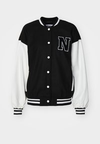 Veste de style universitaire noir et blanc avec un tissu doux, des boutons-pression, des poignets côtelés et un grand "N" brodé sur la poitrine.