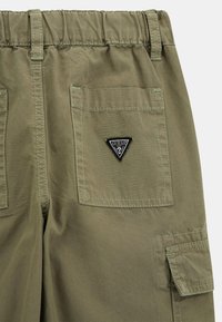 Olijfgroene cargobroek met een rekbare tailleband, een achterzak met een zwart driehoekig logo en zichtbare stiksels.