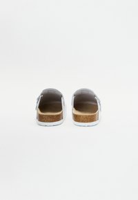 Sandale albe tip slip-on cu curea gri, talpă din plută și talpă din cauciuc texturat; design minimal, spate deschis pentru a fi ușor de purtat.
