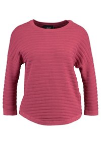 Różowy sweter z ribbowanym wzorem, okrągłym dekoltem i rękawami o długości trzech ćwierci. Bardzo lekko zaokrąglony dół, podkreślający poziomy wzór na tkaninie.