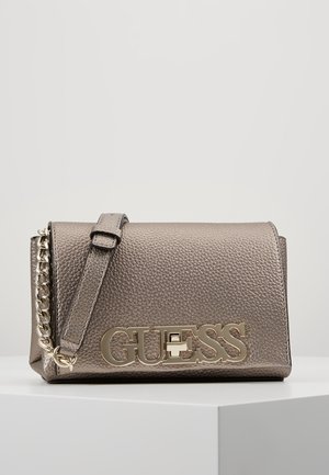 Sac bandoulière en cuir texturé gris métallique avec bandoulière réglable et détail chaîne dorée, présentant un grand logo GUESS doré sur le rabat avant.