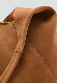 Brown suede ankle boot featuring a fold-over design, smooth texture, and diagonal stitching details along the side.