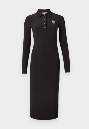 Μαύρο μακρυμάνικο φόρεμα πόλο με γιακά, διαθέτει κουμπωτή λωρίδα και διακοσμητική ραφή σε σχήμα ρόμβου στο αριστερό στήθος.