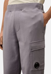 Graue Baumwoll-Jogginghosen mit schmaler Passform, elastischem Bund, seitlichen Taschen und einer aufgesetzten Tasche mit Logo-Detail.