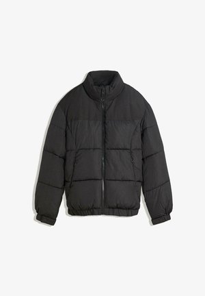 Fekete puffermellény magas gallérral, cipzárral és elasztikus mandzsettákkal. Vízszintesen steppelt részek és oldalsó zsebek jellemzik.