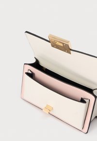 Portefeuille compact en cuir blanc, rose et noir. Doté d'une fermeture à fermoir doré et d'une poche intérieure. Texture lisse, lignes de design épurées.