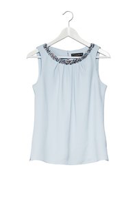 Blusa sin mangas de color azul claro con un frente plisado y un escote adornado con cuentas de colores y lentejuelas. Cuela en una percha blanca.
