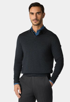 Dunkelgrauer Strickpullover mit Kragen, ausgestattet mit einer Knopfleiste und langen Ärmeln; darunter kombiniert mit einem blauen Hemd.