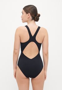 Black swimsuit with a racerback design and a cut-out back detail. Made from smooth fabric, it features a snug fit and no visible patterns.