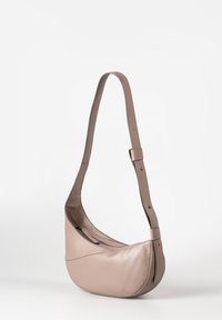Zachte beige leren schoudertas met een gebogen vorm, verstelbare schouderriem en ritssluiting, met een gladde textuur en naadloos ontwerp.