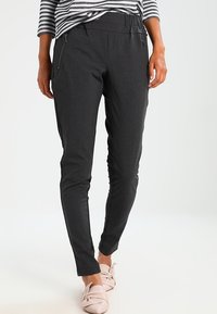 Dark gray tailored pants with a smooth, slightly textured fabric. Features side zip pockets and a tapered leg design. Paired with light pink flats.