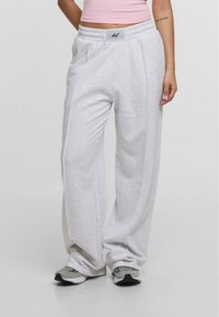 Grå sweatpants med løs pasform, lavet af blødt stof, med elastisk talje og sidesømme. Båret med grå sneakers.
