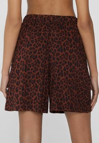 Pantalones cortos de estampado de leopardo marrón con cintura elástica, que presentan un corte suelto y longitud hasta mitad del muslo. Tejido suave con un ligero brillo.