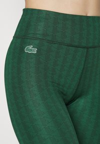 Zielone legginsy z geometrycznym wzorem i małym haftowanym logo. Wykonane z elastycznego materiału z wysokim pasem.