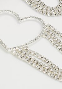 Accesorios para el cabello de plata con un diseño en forma de corazón adornado con gemas transparentes, detalles intrincados y un acabado texturizado.