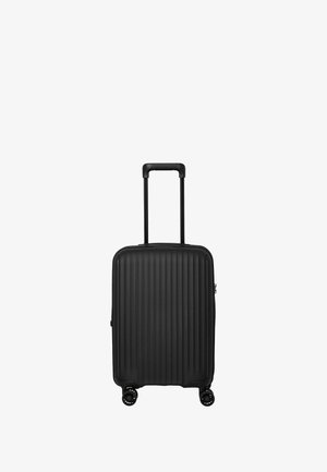 Valise rigide noire avec un motif de rainures verticales, poignée télescopique et quatre roues pivotantes. Design compact et de forme carrée.