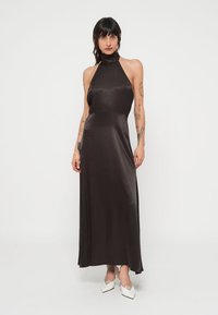 Fekete szatén pántos ruha, amely testhez simuló felsőrésszel és lágyan omló szoknyával rendelkezik, magas nyakrésszel és sima, fényes textúrával.