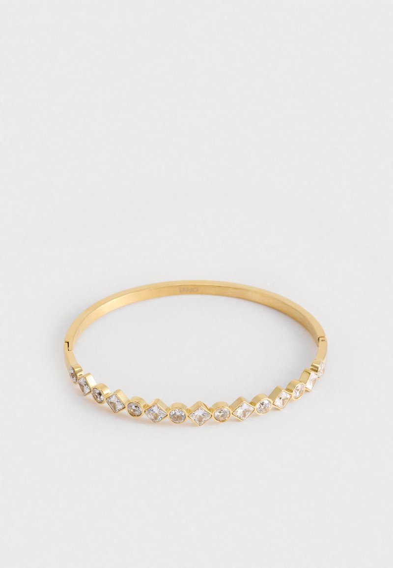 Bracciale rigido in oro con gemme trasparenti sfaccettate disposte in forme rettangolari e a diamante alternate sul fronte. Finitura superficiale liscia.