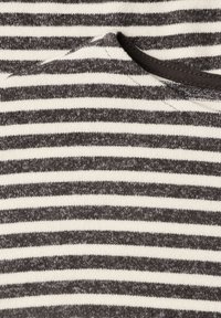 Gros plan d'un tissu à rayures horizontales noires et blanches avec un détail de bord de col, montrant la texture et les coutures.