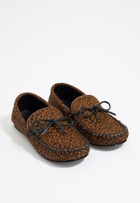Mocasines de leopardo marrón con cordones negros, material suave, punta redondeada y costura decorativa a lo largo de los bordes. Suelas planas.