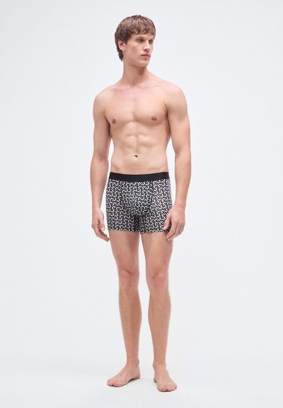 Μαύρα και άσπρα boxer briefs με σχέδιο, εφαρμοστή γραμμή και ελαστική ζώνη στη μέση. Το υλικό φαίνεται μαλακό με λεία υφή.