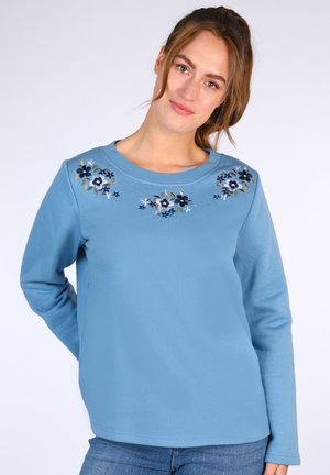 Hellblaues Sweatshirt mit floraler bestickung in Marineblau und Pastellfarben am Halsausschnitt. Lange Ärmel und runder Kragen.