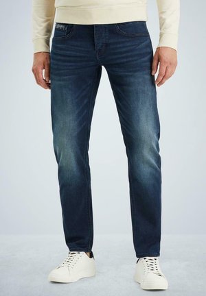 Blauwe spijkerbroek met een slim fit, medium was met vervaging en een klassiek vijf-pocketontwerp, gecombineerd met witte sneakers.