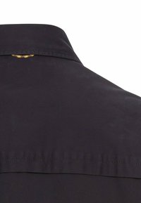 Zwarte kraag met een gladde textuur; voorzien van een gele en zwarte patroonaccent onder de kraag.