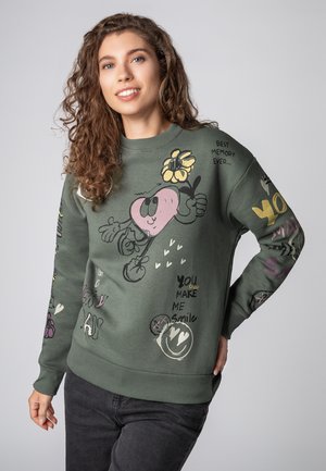 Olive green sweatshirt featuring colorful graphic prints, including a heart character, flowers, and various text patterns. Ribbed cuffs and hem.