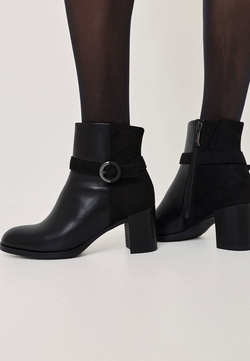 Mustad mustad kingad, mis on valmistatud sileda nahast ja sametist, ümarate varvastega, paksu plokknõgaga, vöödetailiga ja külgrihmakummutiga.