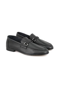 Schwarze Lederloafers mit strukturiertem Finish, ausgestattet mit einem dekorativen Riemen und metallischen Beschlägen. Elegante Form und niedrige Sohle.
