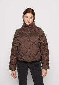 Veste matelassée en brun avec un col haut, un design cropped et des fermetures à bouton. Présente une texture brillante et lisse ainsi que des motifs diagonaux.