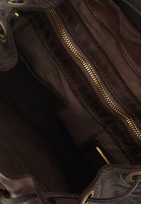 Interno di una borsa a tracolla in pelle marrone con sezioni lisce e strutturate, multipli scomparti, una cerniera dorata e foderato in tessuto scuro.